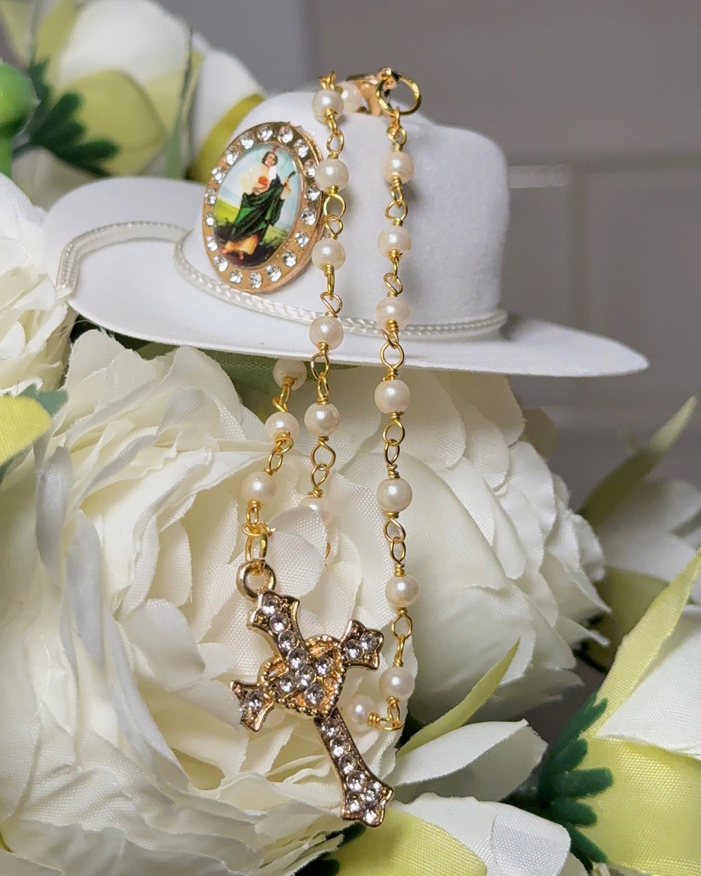Gold necklace with a cross pendant on a white flower background