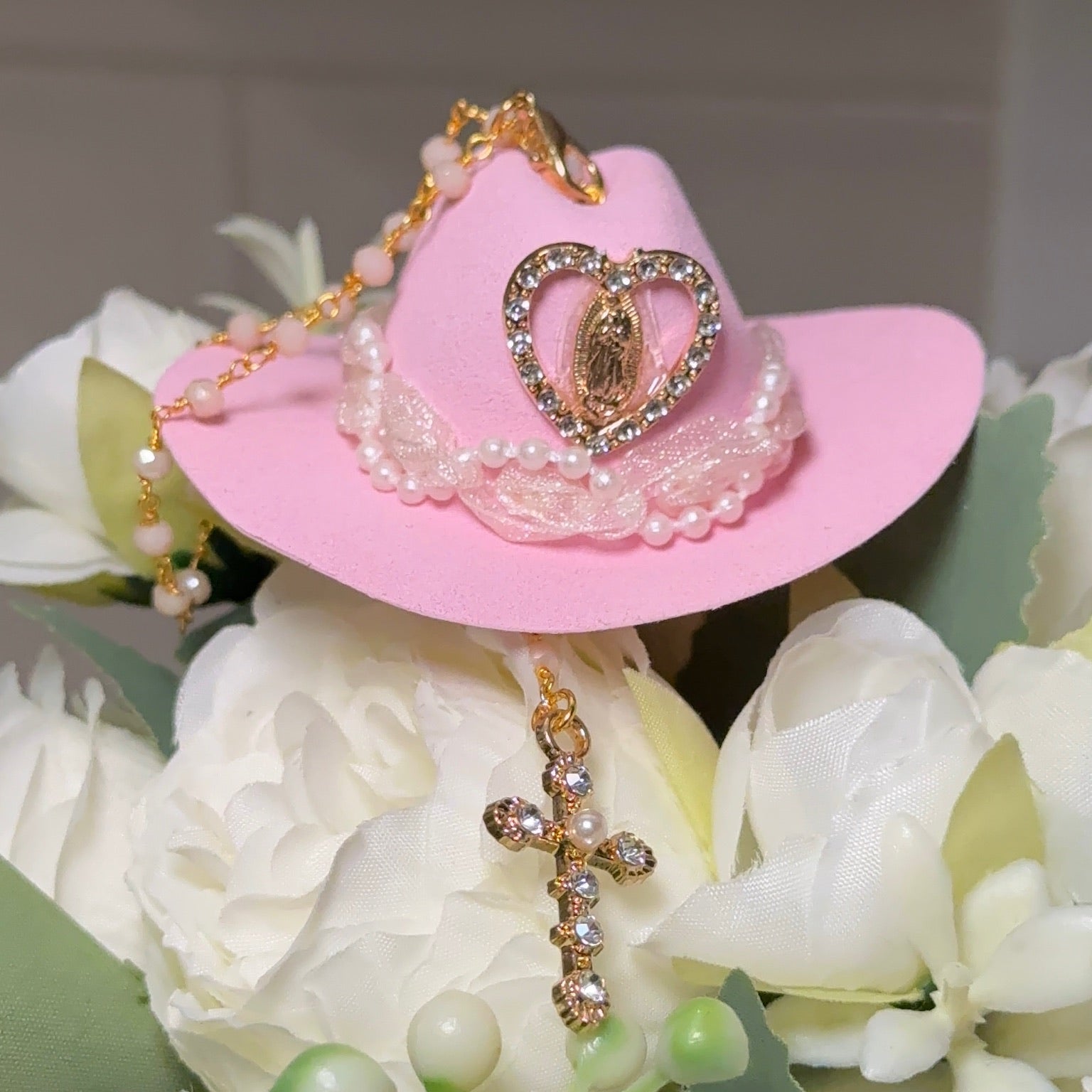 Pink cowboy hat with heart design on a bouquet of white flowers.