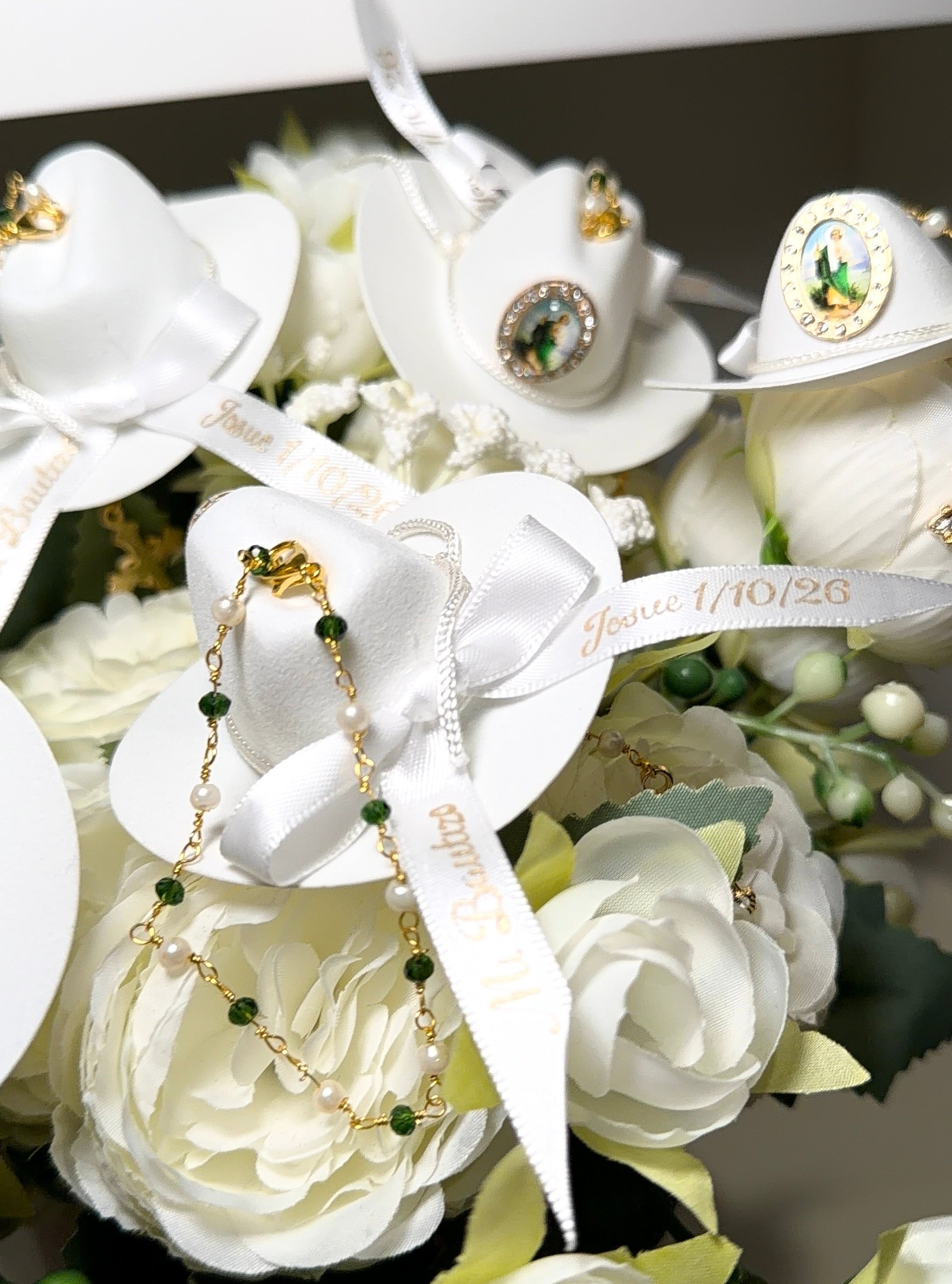 White floral arrangement with decorative ribbons and small green beads on a white background